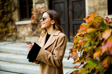 Modern woman using mobile phone at autumn outdoor