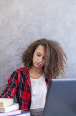 Curly hair teen girl websurfing internet on laptop at home