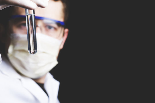 chemist holds a test tube with clear liquid in his hands