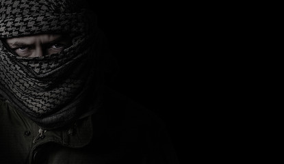 angry soldier in a camouflage scarf shemag on a black background