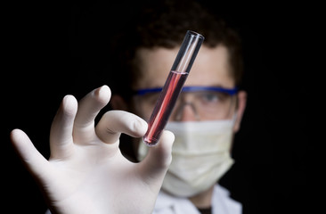 chemist holding a test tube with red liquid on a black background