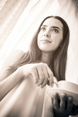Naklejka premium beautiful happiness caucasian girl enjoy morning moment with hot coffee in white tshirt with light from white curtain