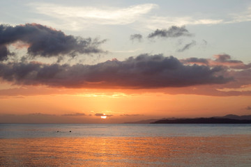 beautiful sunset over a tropical sea with two people doing snorkeling