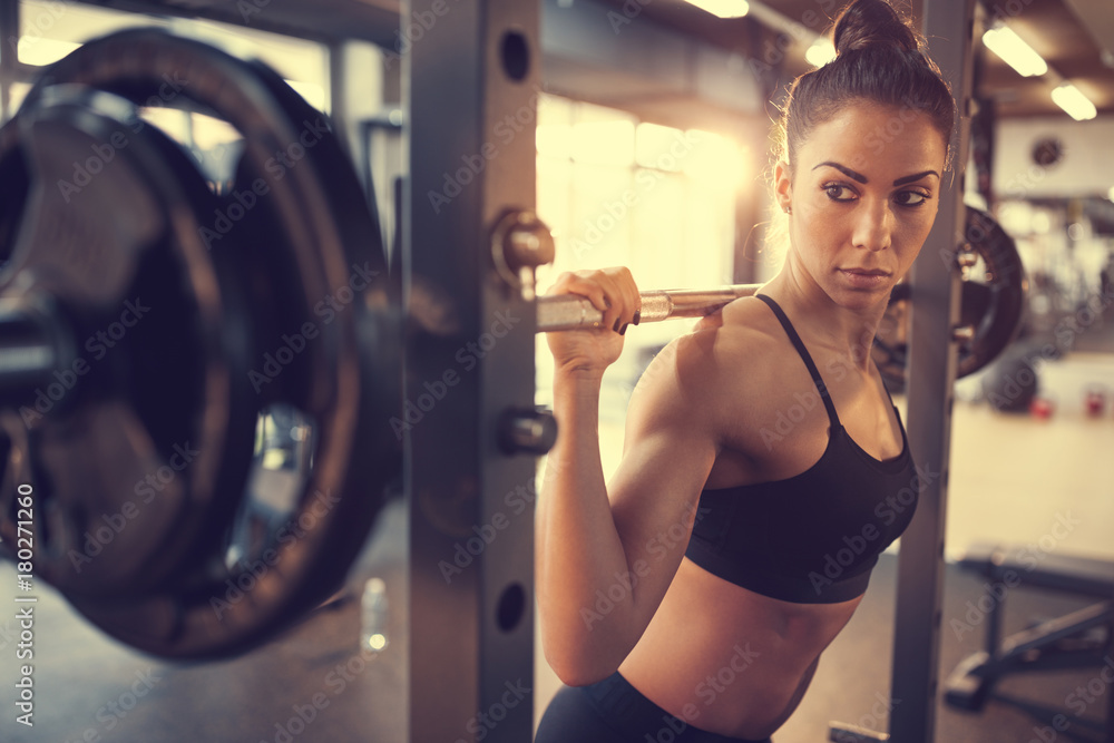 Wall mural young female doing exercise with barbell