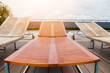wooden bench on wooden deck nearby swimming pool