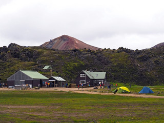 Gruop of hikers in front of landmannalaugar camp site mountain cottage with view on Brennisteinsalda in rainbow hills in Iceland start of famous  Laugavegur trek