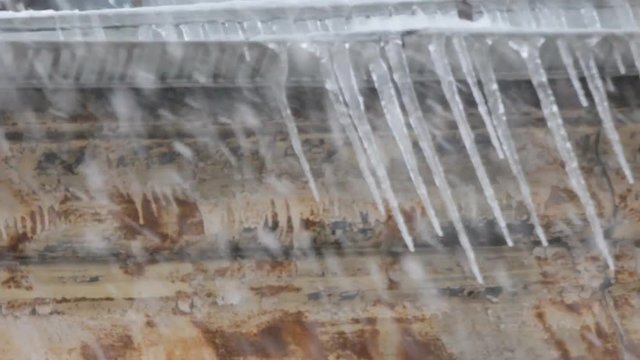 Snowfall in old Northern city. From roof of icicles

