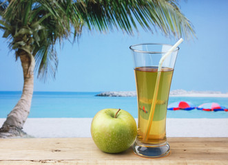 Glass of apple juice on a beach table