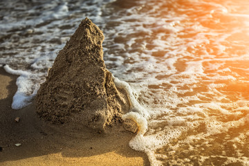 The ruins of a sand castle being swept away by the sea