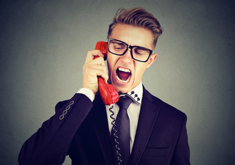 Angry young business man yelling on the phone