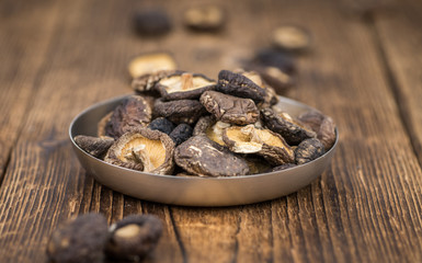 Portion of Shiitake mushrooms (dried) on wooden background, selective focus