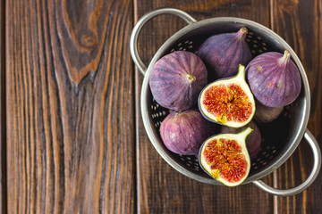 Top view of figs fruits inside metal colander on table.