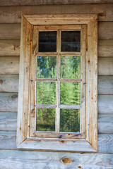 Window of a wooden house, which reflects the forest.