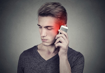 Man on the cellphone with headache. Upset unhappy guy talking on a phone