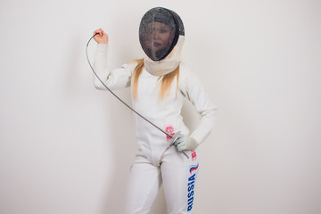 woman wearing fencing suit practicing with sword against grey vignette