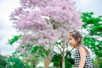 Naklejka premium Portrait of cute little girl on beautiful flowers on tree background,colorful tone