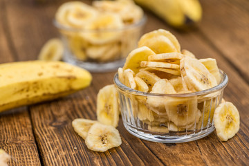 Portion of Dried Banana Chips on wooden background, selective focus