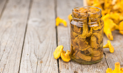 Wooden table with Canned chanterelles, selective focus