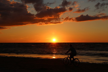 Fototapeta premium Man cycling along the Baltic Sea shore in Jurmala, Latvia at sunset