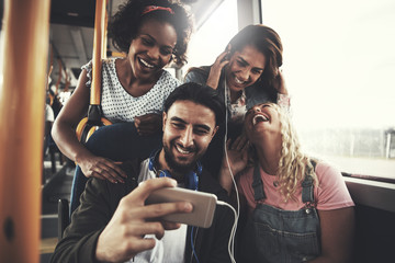 Smiling friends listening to music together on a bus