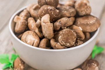 Portion of Raw Shiitake mushrooms on wooden background, selective focus