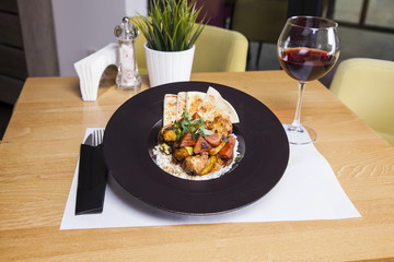 Fried chicken fillet, boiled potatoes and vegetables in black plate,isolated