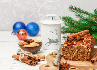 Fototapeta na wymiar Homemade holiday Fruitcake with nuts, fruits and spices. Almonds, cinnamon, star anise, cardamom on the table. Traditional English pastries. Christmas. New year. Selective focus