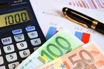 Euro banknotes with calculator, pen, glasses and paperwork. Business concept image.
