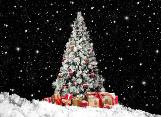 festlich geschmückter Christbaum im Schnee mit vielen Geschenkpaketen