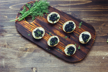 Fototapeta na wymiar Top view of black caviar appetizers at wooden board.