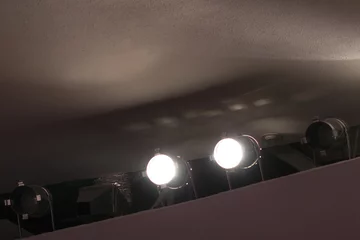 Cercles muraux Lumière et ombre Deux spots lumineux brillent sous le plafond de la salle de concert.
