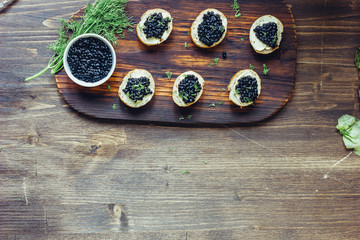 Obraz na płótnie Canvas Top view of black caviar appetizers at wooden board.