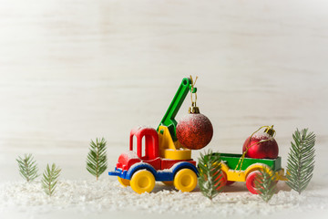 New Year's wood with firs and a toy crane, which raises a Christmas tree toy. Billet for postcards or congratulations. Copy space