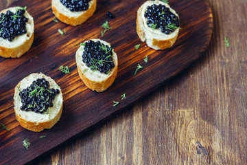 Appetizer for christmas table - black caviar on the pieces of bread.