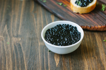 Fototapeta na wymiar Fresh black caviar in a white ceramic bowl.