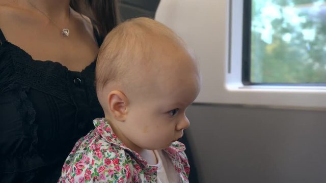 A baby girl eating a flat biscuit on the train. Close-up shot.