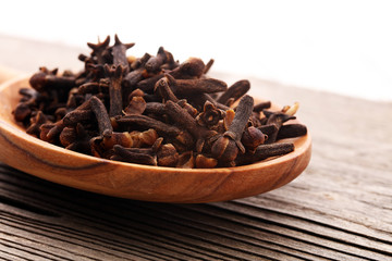 Many Dry cloves spice on brown wooden spoon.