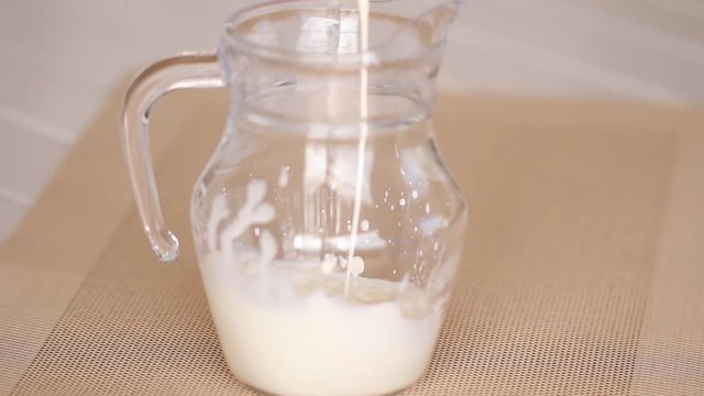 Liquid cream poured into a pitcher spash on the glass.