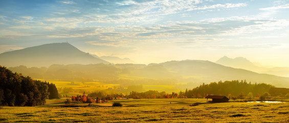Breathtaking lansdcape of Austrian countryside on sunset. Dramatic sky over idyllic green fields of Anstrian Central Alps on autumn evening.