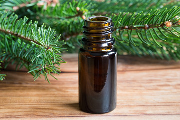 A bottle of spruce essential oil with spruce branches