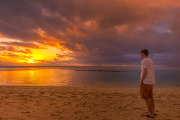 Fototapeta na wymiar Blick auf den Sonnenuntergang am Meer mit einem Mann
