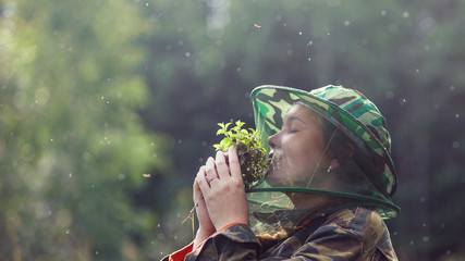 Woman in mosquito netsmelling peppermint bouquet in forest