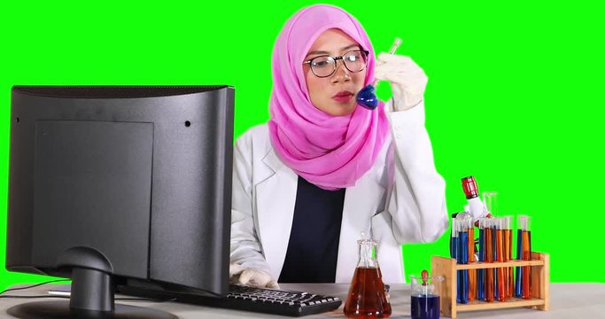 Muslim scientist working with computer and test tube on the table. Shot in 4k resolution with green screen background