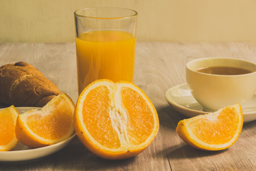 A glass of orange juice, a sliced orange and a cup of tea with a croissant and pieces of cane sugar - a healthy diet concept, a light breakfast