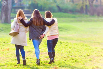 Fototapeta premium Three female friends walking in park