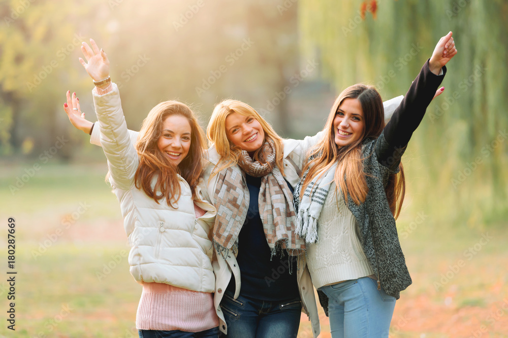 Wall mural portrait of three smiling female friends in park. best friends - girl power