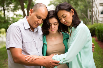 Obraz premium Portrait of a family praying with their daughter.