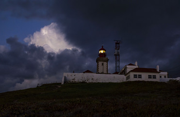 Fototapeta na wymiar Dramatic night Portuguese landscape on the coast of Atlantic Ocean, the westernmost point of mainland Europe at Cabo da Roca. Old Lighthouse.