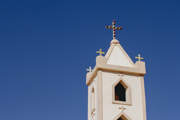 tower of a rural church on the blue sky as background