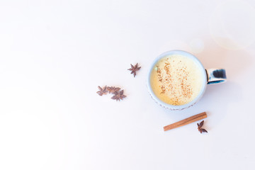 Top view image of turmeric latte over white wooden table with copyspace. Turmeric Latte with Nut Milk, cinnamon, honey, ginger
